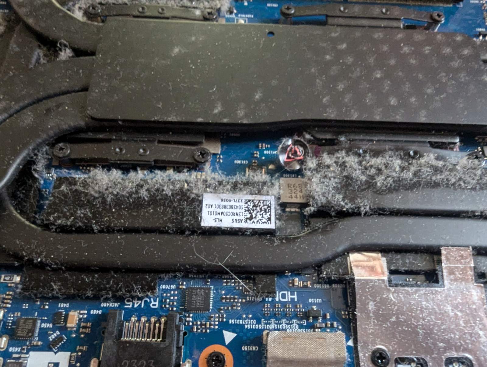 Материнська плата ноутбука Asus з пилом Материнська плата ноутбука Asus G713P зі скупченням пилу навколо важливих компонентів. Засмічення пилом може призвести до зниження ефективності охолодження та можливих несправностей.