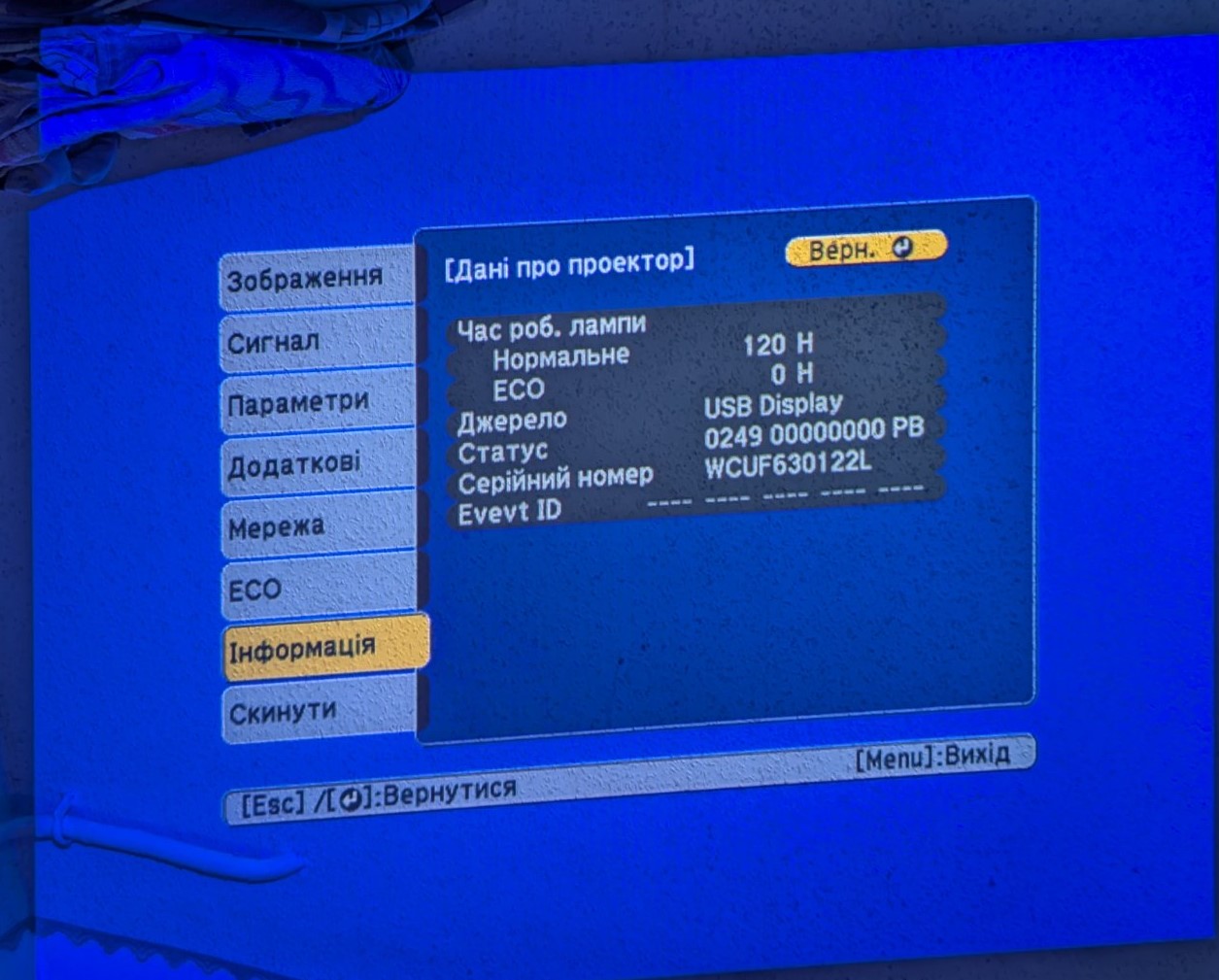 epson-projector-menu-display-info.jpg Зображення меню проектора Epson з інформацією про роботу лампи, серійний номер і джерело сигналу, відображене на синьому екрані.