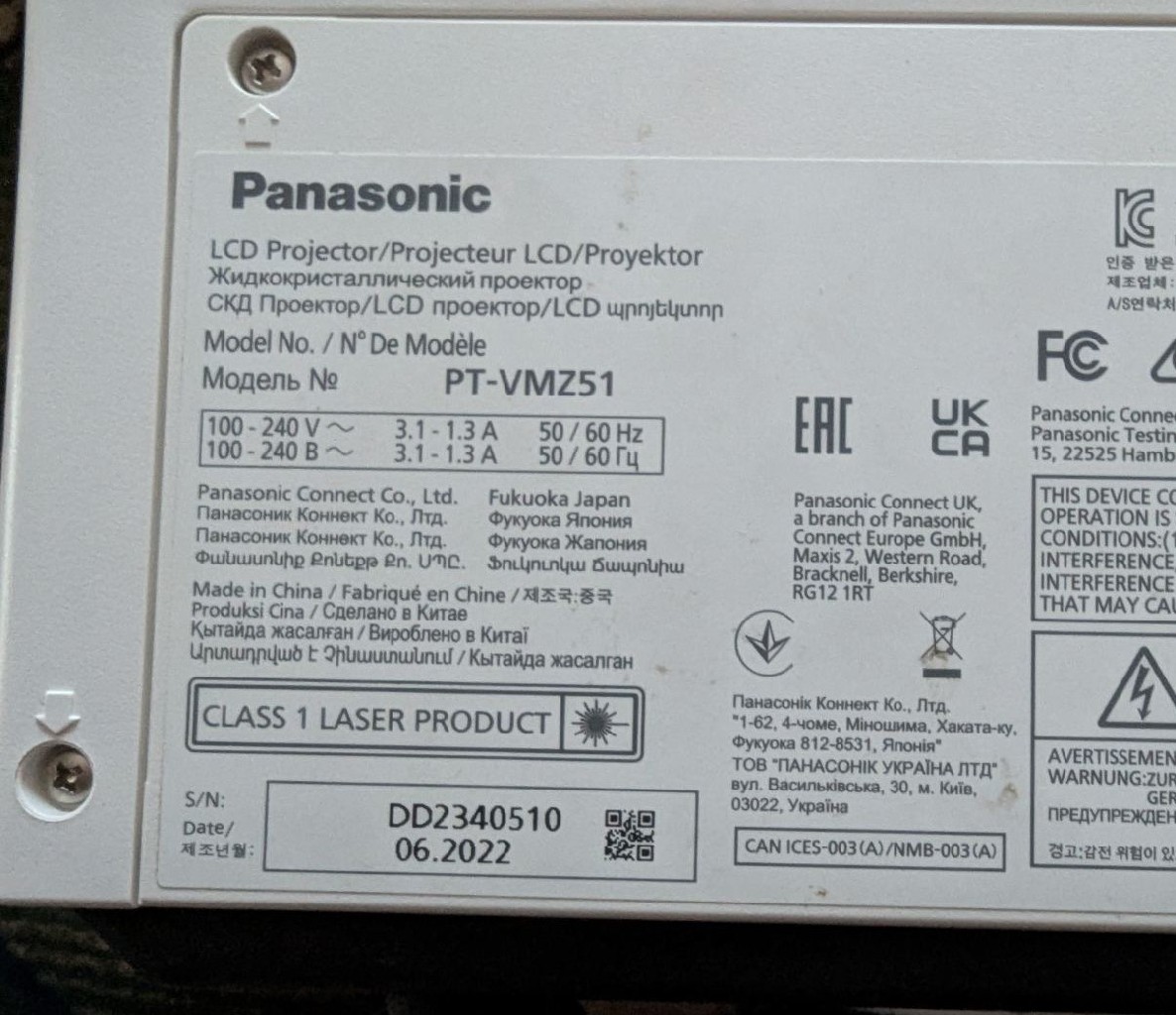 На зображенні показано інформаційну табличку проектора Panasonic PT-VMZ51. На ній зазначені технічні характеристики пристрою, зокрема діапазон вхідної напруги (100-240V), споживаний струм (3.1-1.3A), а також частота роботи (50/60Hz). Також є серійний номер, дата виробництва (06.2022) та відомості про виробника — Panasonic Connect Co., Ltd. Крім того, табличка містить маркування відповідності європейським та міжнародним стандартам.