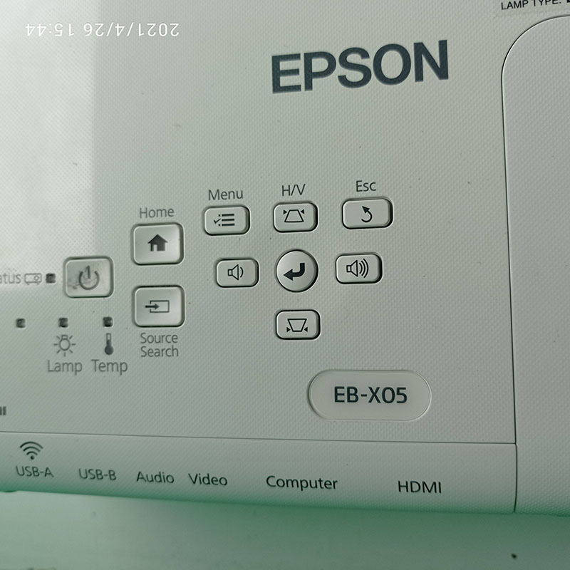 Панель управління Epson EB-X05 із індикаторами та портами підключення Панель управління проектора Epson EB-X05 із кнопками для налаштування зображення, вибору джерела сигналу та регулювання параметрів. Видно функціональні індикатори лампи та температури, а також порт HDMI та інші роз'єми для підключення.
