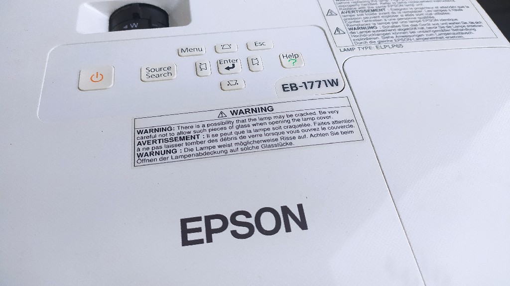 Проектор Epson EB-1771W – заміна лампи ELPLP65 Зовнішній вигляд проектора Epson EB-1771W, модель із попередженням про безпечну заміну лампи ELPLP65.