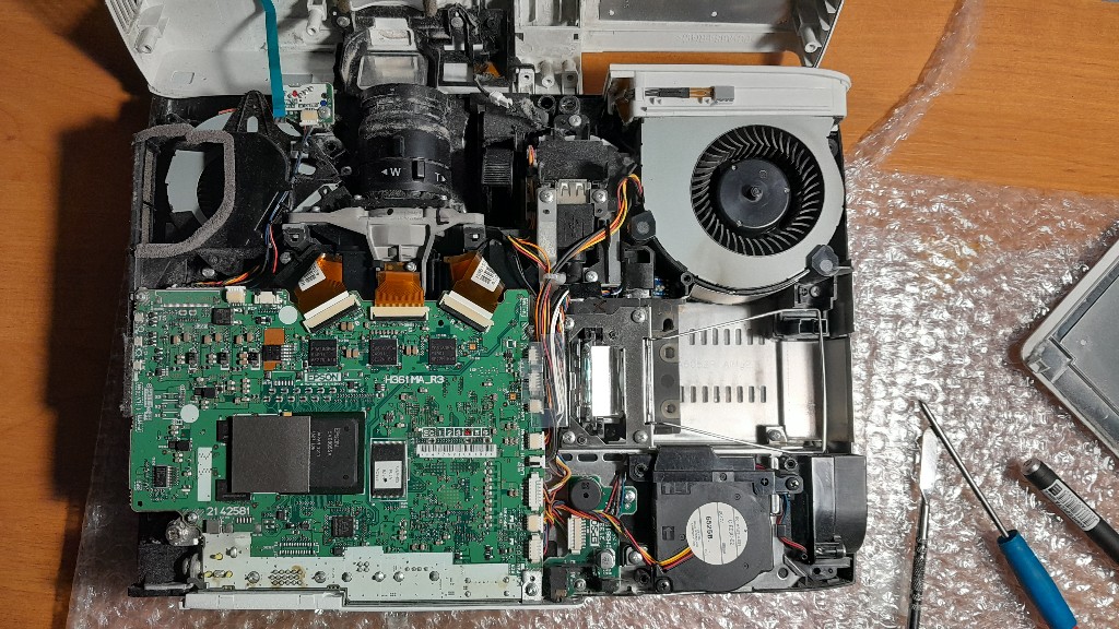 Внутрішня будова проєктора Epson H477B – ремонт і обслуговування внутрішню будову проєктора Epson LCD Projector Model H477B, зокрема основну плату, систему охолодження, лінзи та інші ключові компоненти. Видно значне накопичення пилу, що може призводити до перегріву та зниження продуктивності пристрою