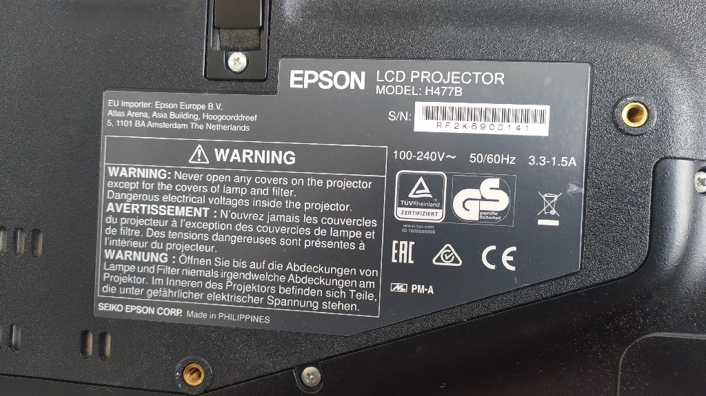 Задня панель проєктора Epson H477B – технічні характеристики та сертифікація задня панель проєктора Epson H477B з інформаційною наклейкою, яка містить технічні характеристики, попередження щодо безпеки та сертифікати відповідності.