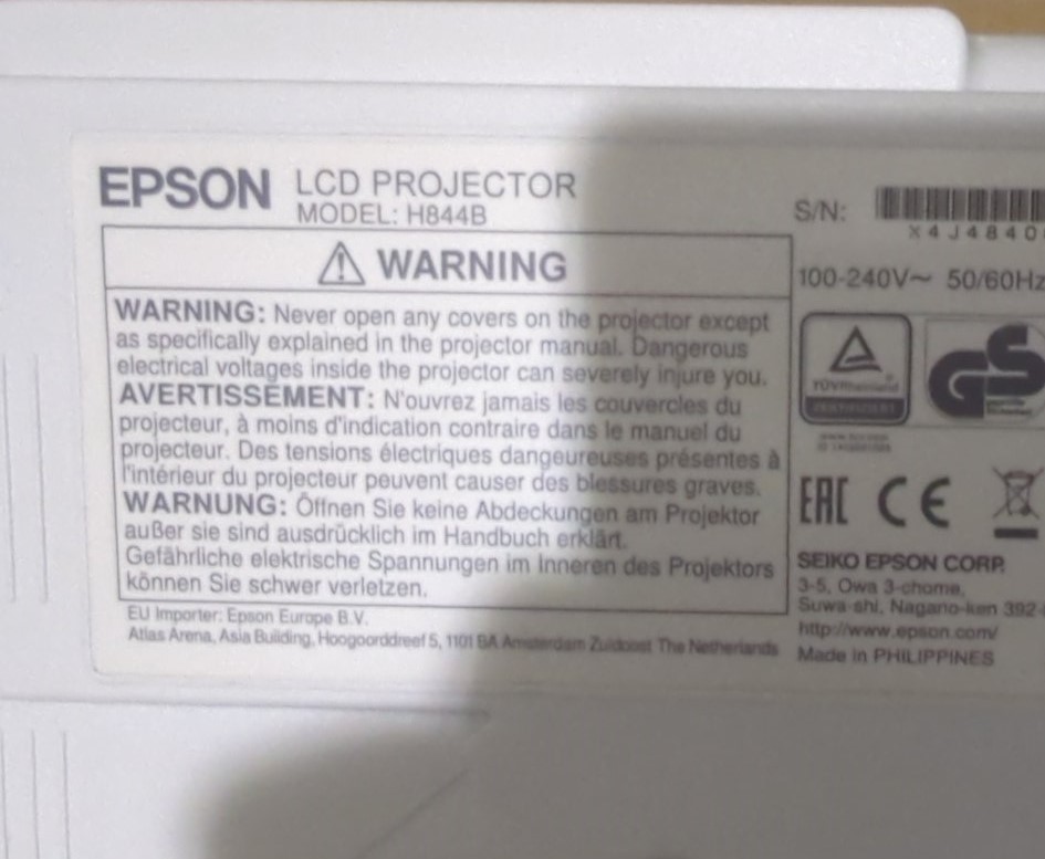Epson H844B попередження про безпеку. Етикетка на проекторі Epson моделі H844B з попереджувальним повідомленням про небезпеку електричного удару при відкритті корпусу.