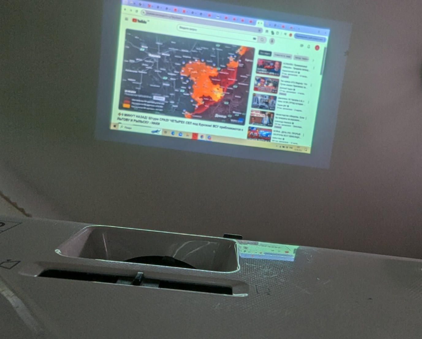 Проекція відео з YouTube через проектор Epson на стіну Проекція на стіні зображення з YouTube, де видно відео-карту з новинами. Зображення проектується за допомогою проектора Epson, частина якого також потрапила в кадр.